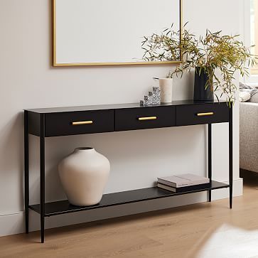 a white vase sitting on top of a wooden table next to a black and gold shelf