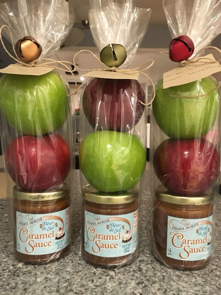 three jars filled with apples sitting on top of a counter next to bags of food