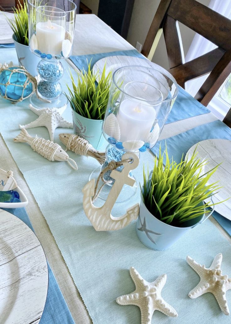 the table is set with blue and white dishes, seashells, and candles