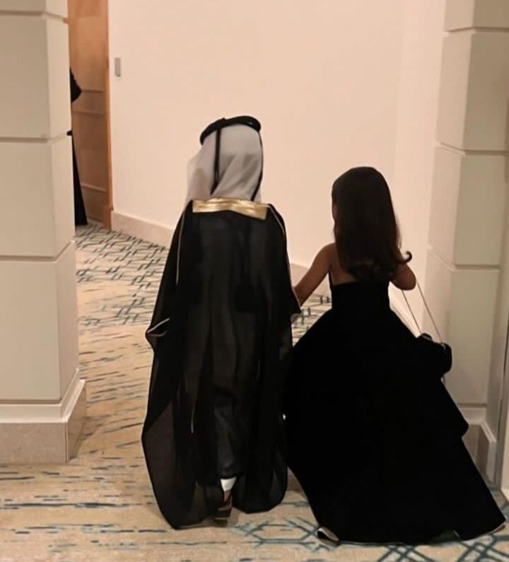 two women dressed in black sit on the floor and look at each other's back