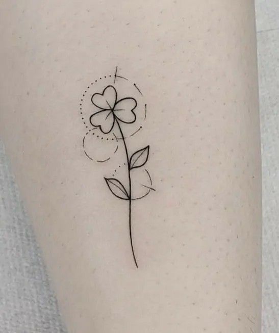 a small flower tattoo on the left side of the leg, it is black and white