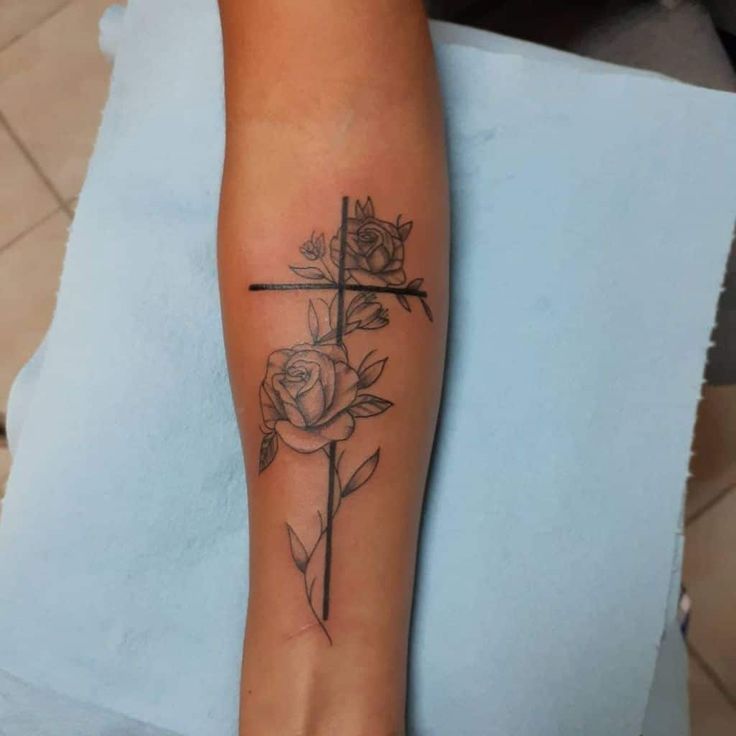 a woman's foot with a cross and roses tattoo on the side of her leg