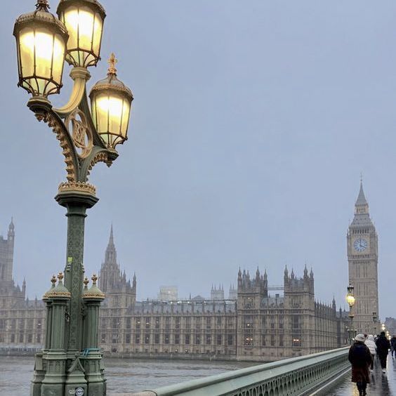 people walking on a bridge in front of big ben and the houses of parliament, london