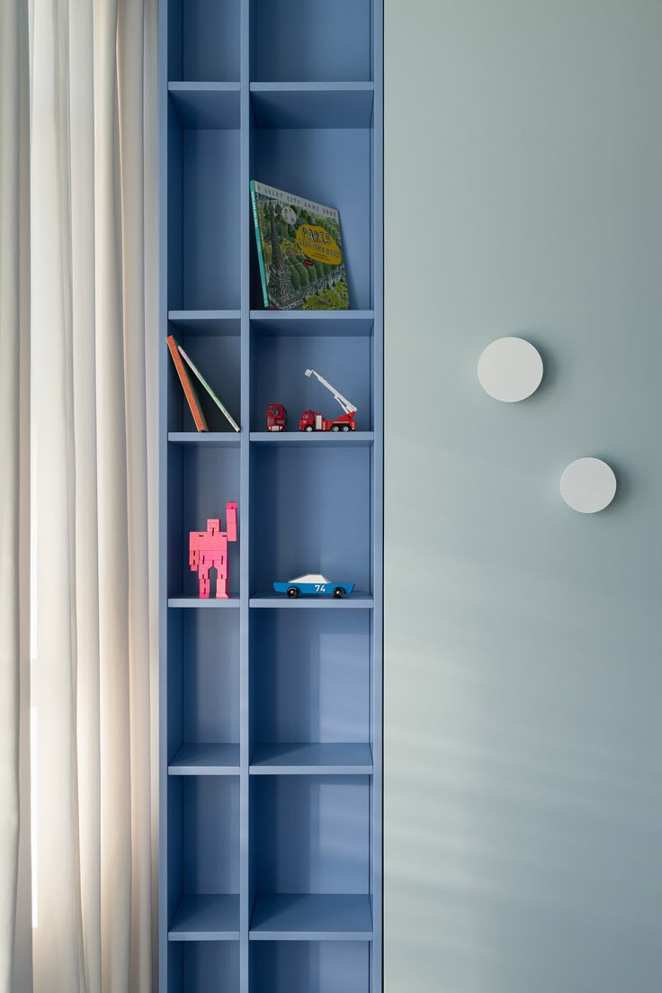 a blue book shelf with books and toys on it