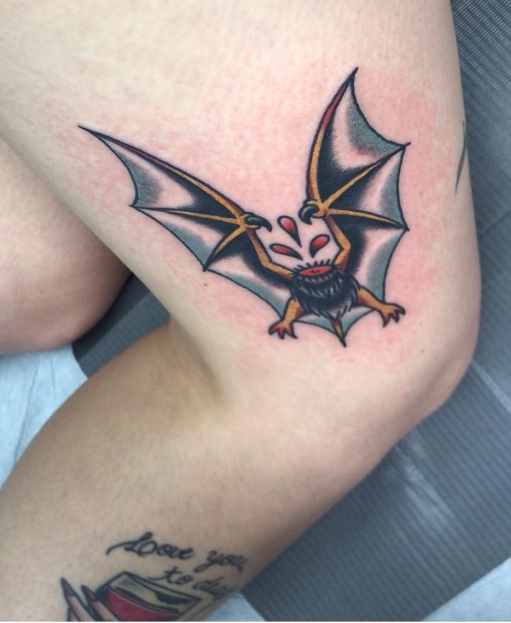 a small bat tattoo on the thigh