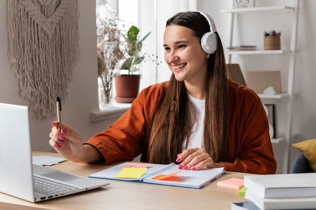 a woman sitting at a desk with headphones on and notebook in front of her