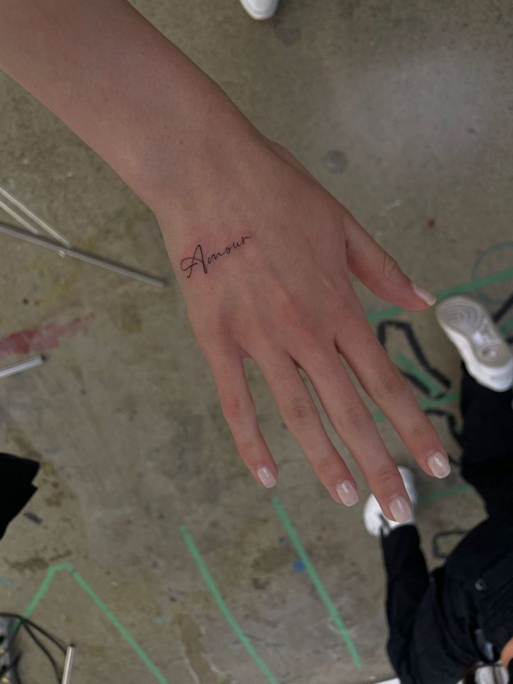 a person's hand with a small tattoo on their left wrist and the word alive written in cursive writing