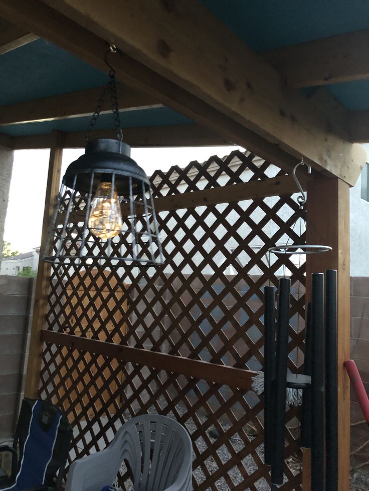 an outdoor patio area with chairs and a light fixture hanging from the ceiling above it