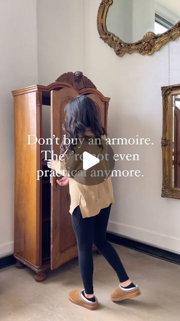 a woman standing in front of a wooden cabinet and looking at her reflection on the mirror