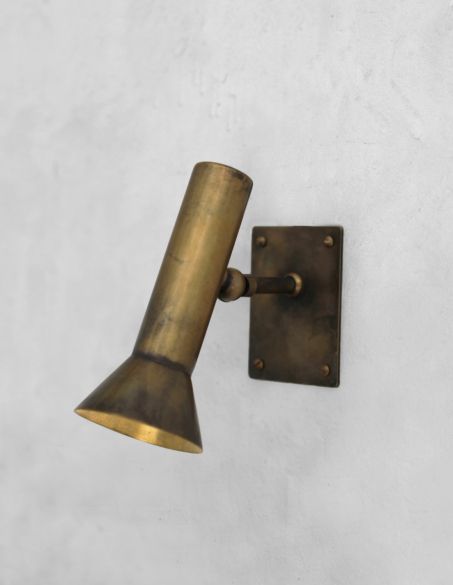 an antique brass wall light on a white wall