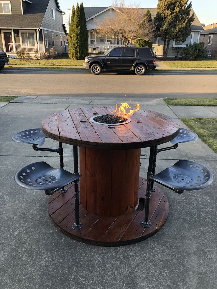 a fire pit sitting on top of a wooden table in the middle of a sidewalk