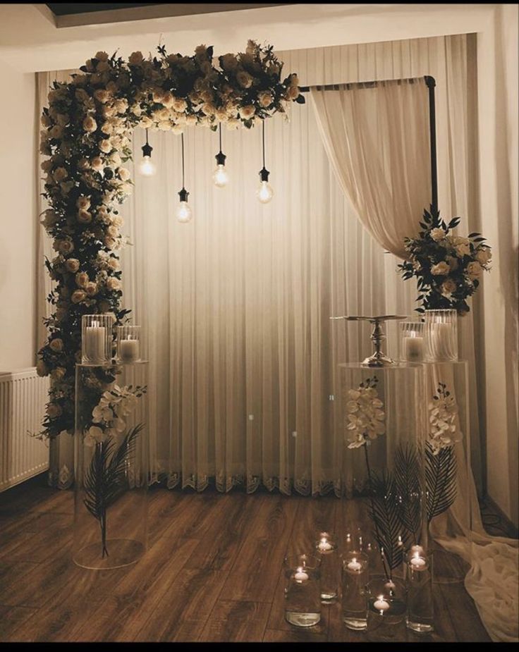 a wedding ceremony with candles and flowers on the floor in front of a sheer curtain