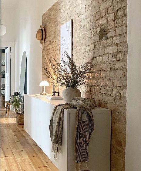 a living room with a brick wall and wooden flooring next to a white cabinet