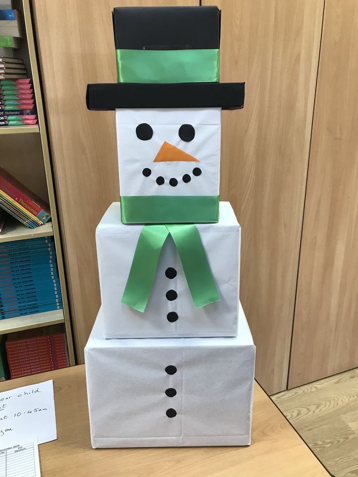 a snowman made out of paper sitting on top of a desk next to a pile of books