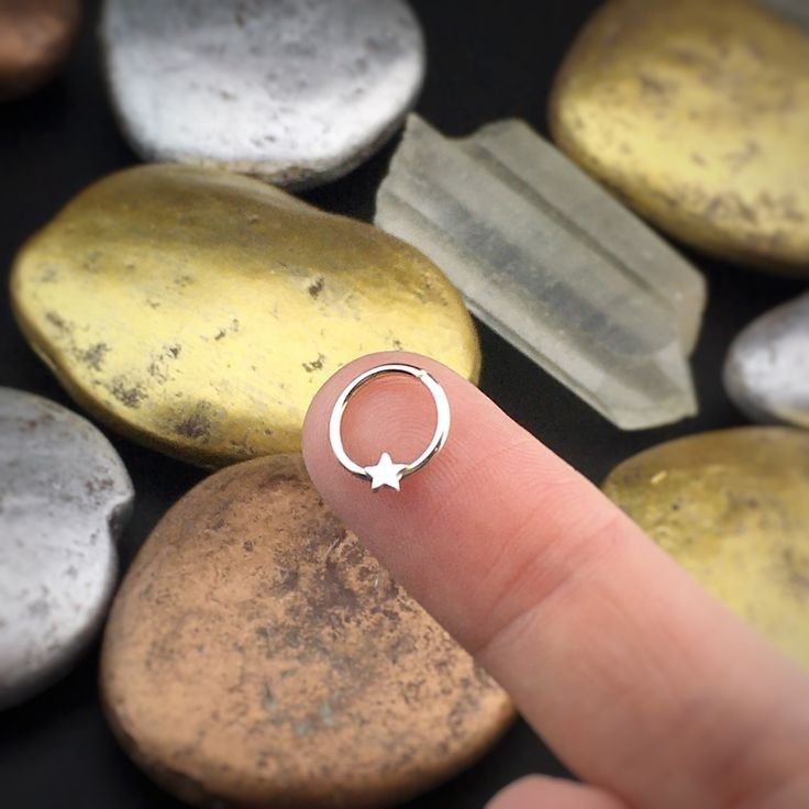 a person's finger with a ring on top of them next to some rocks