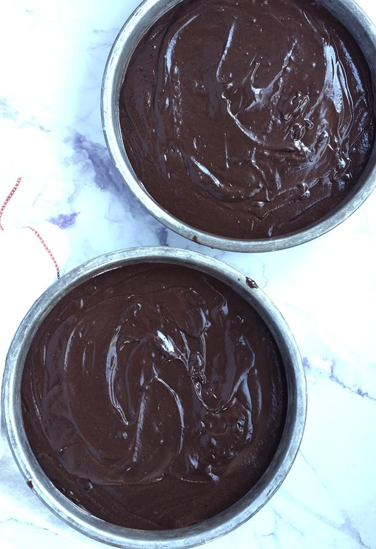 two metal pans filled with chocolate cake batter