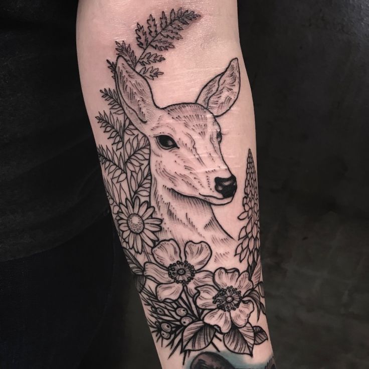 a black and white deer with flowers around it's head on the left arm