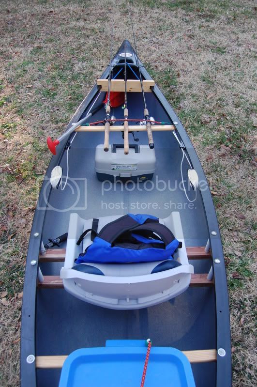 an empty canoe sitting in the grass with a blue cooler on it's side