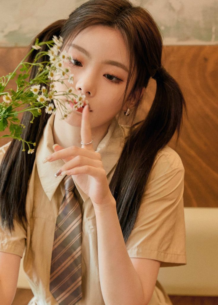 a young woman sitting on a couch holding flowers in her hand and looking at the camera