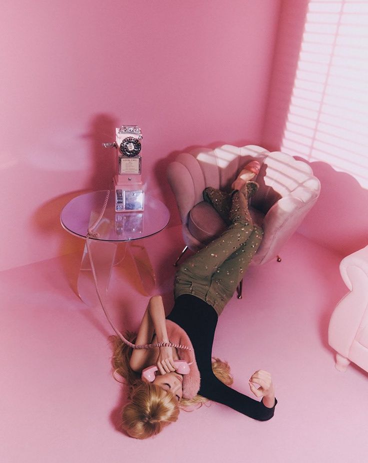 a woman laying on the ground in front of a pink room with a mirror and table