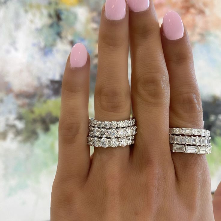 a woman's hand with three different rings on her left and one ring on the right