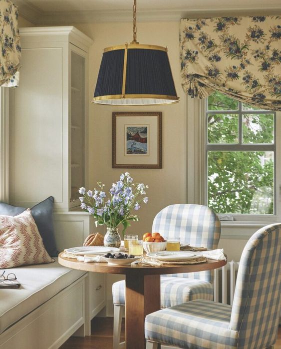 a dining room table with two chairs and a bench in front of a window that has flowers on it