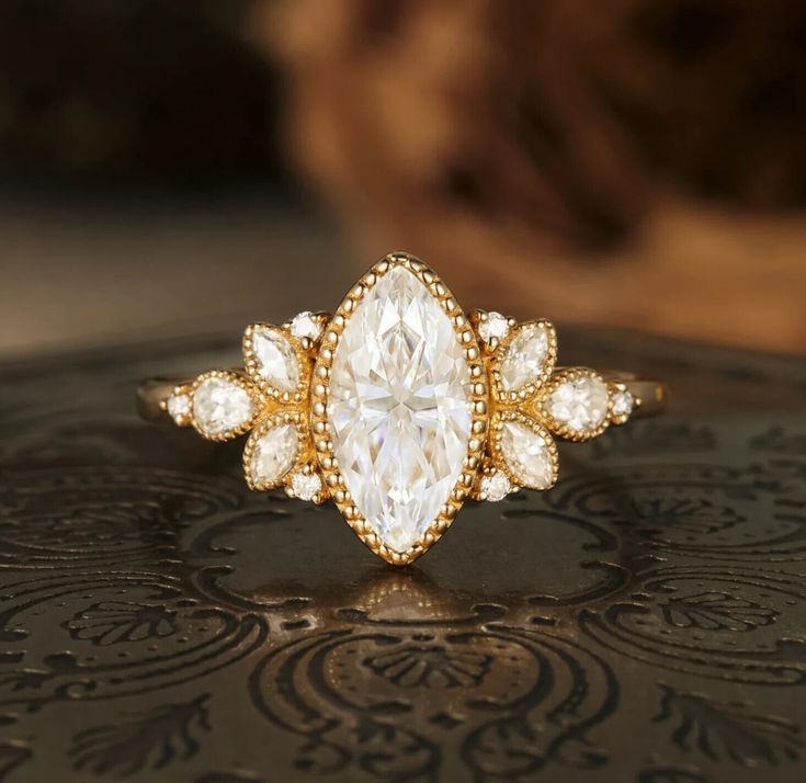 a close up of a diamond ring on top of a black surface with an ornate design