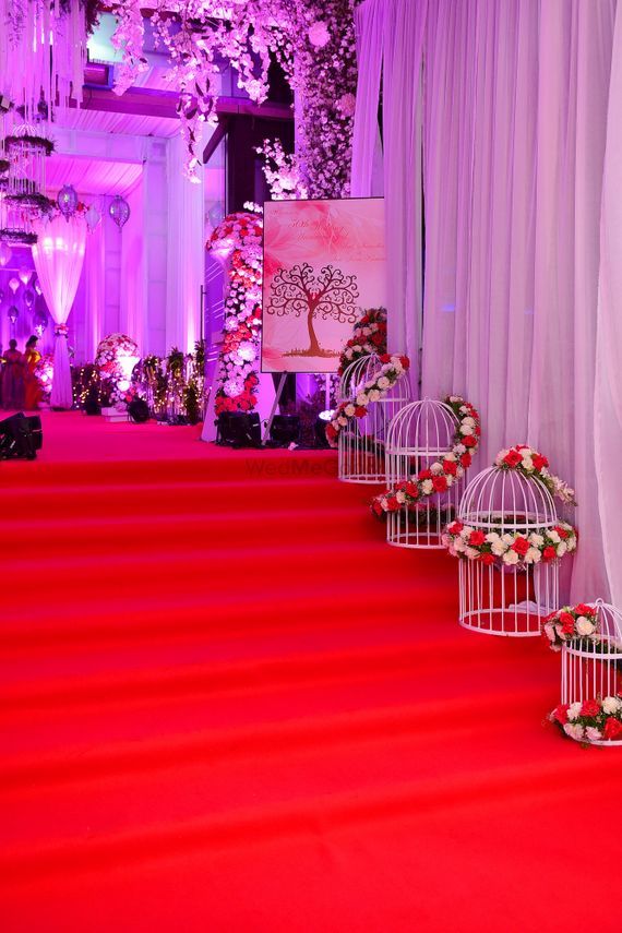 a red carpeted aisle with birdcages and flowers