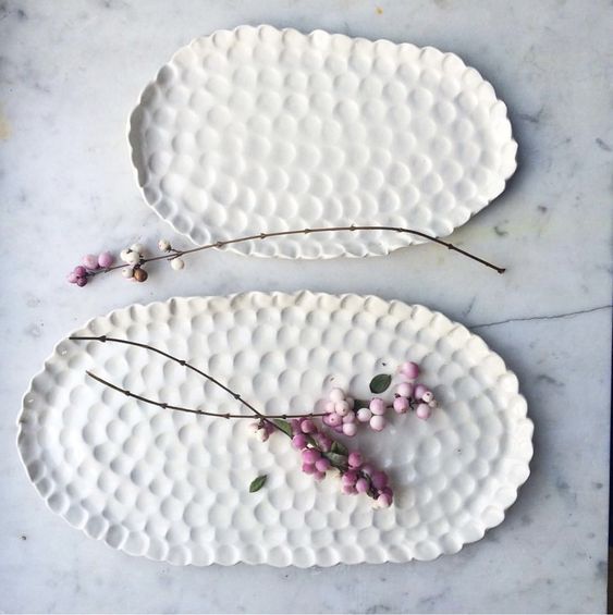 two white plates with flowers on them sitting on a marble counter top next to each other