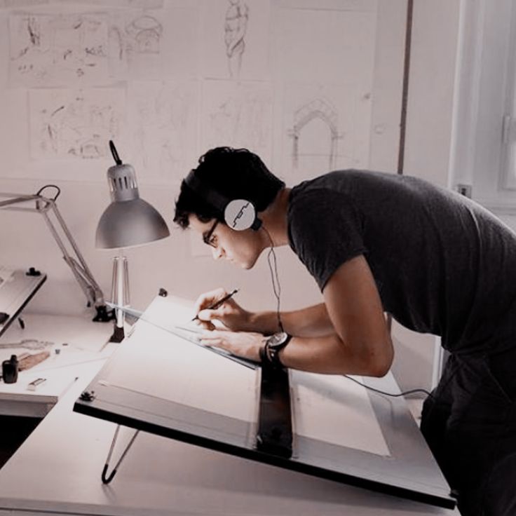 a young man is writing in his notebook while listening to headphones and holding a pen