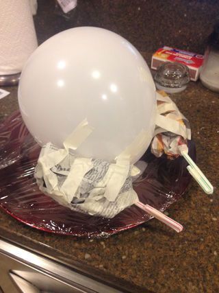 a white ballon sitting on top of a plate covered in tissue paper next to a toothbrush