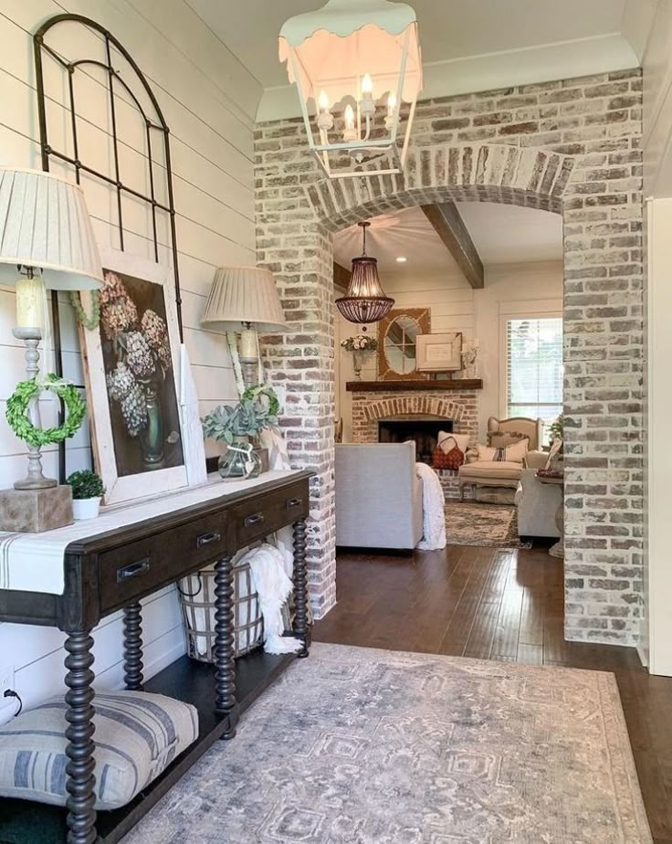 a living room filled with furniture and a fire place next to a brick wall in the background