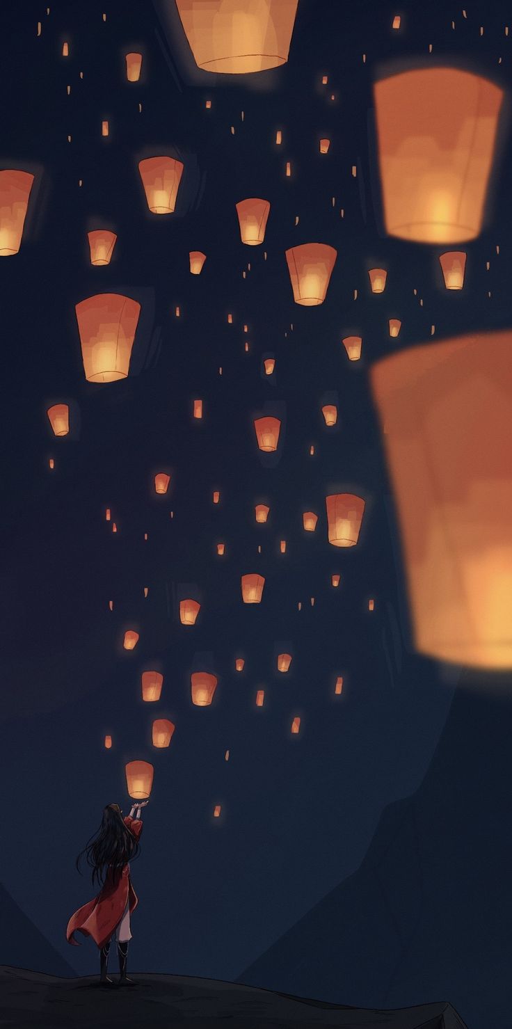 a woman standing on top of a hill next to paper lanterns flying in the sky