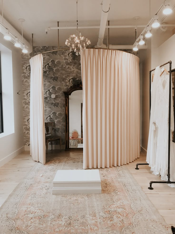 a wedding dress is displayed in front of a curtained room with an area rug