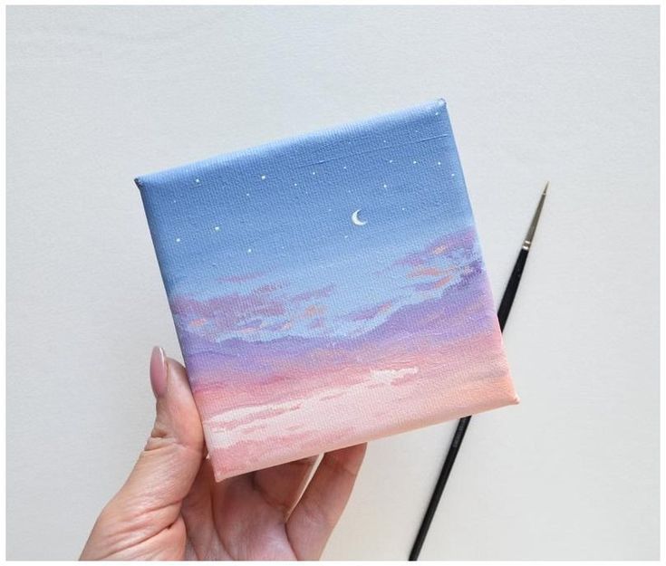 a person holding up a small piece of art that looks like the sky and stars