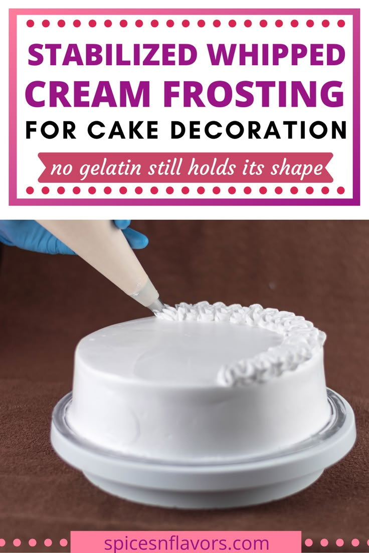 a white frosted cake sitting on top of a table next to a hand holding a knife