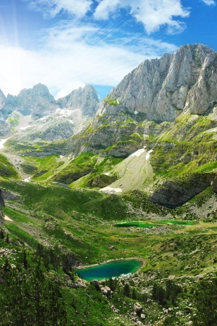 the mountains are covered in green grass and blue water