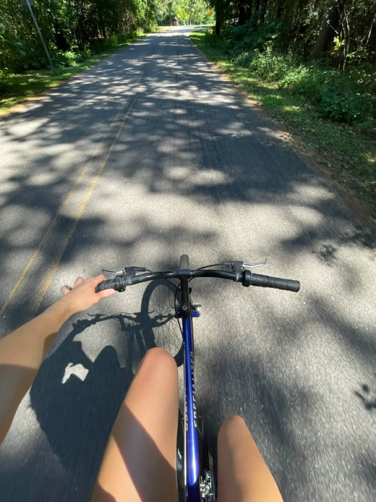 the person is riding their bike down the road in front of them and pointing to the right