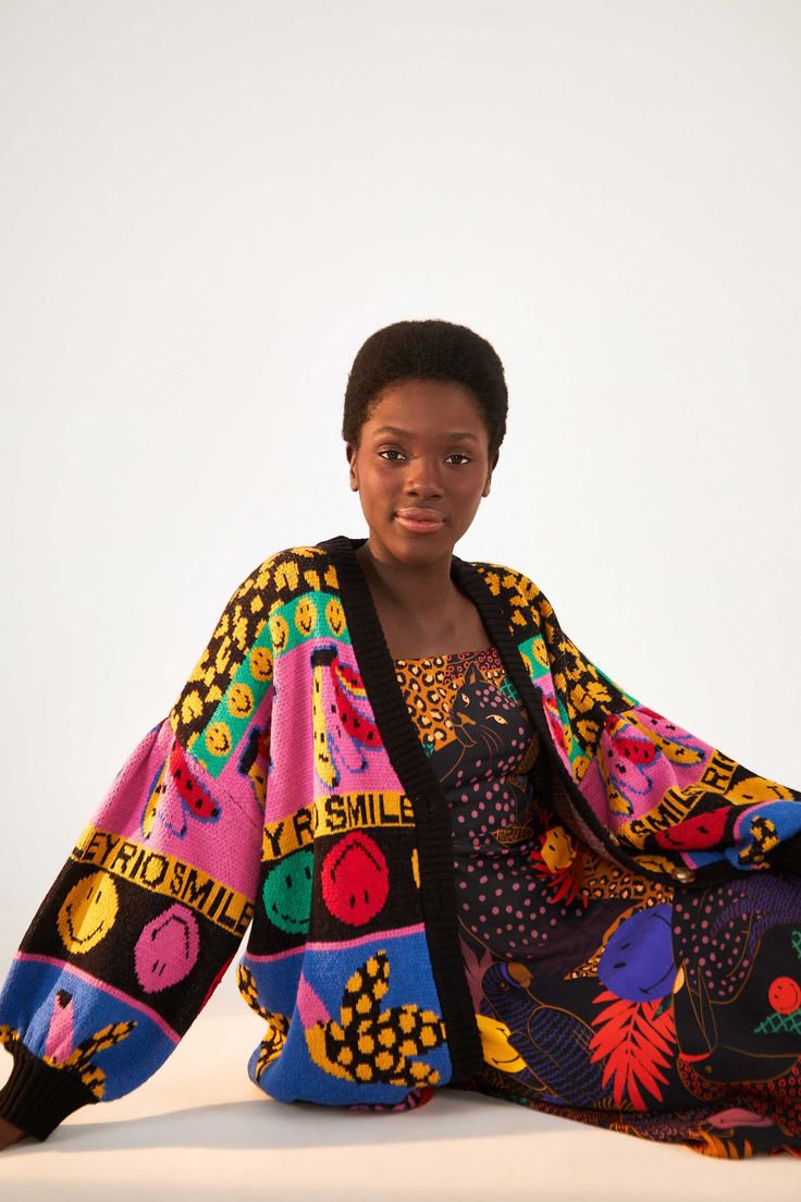 a woman sitting on the ground wearing a colorful blanket