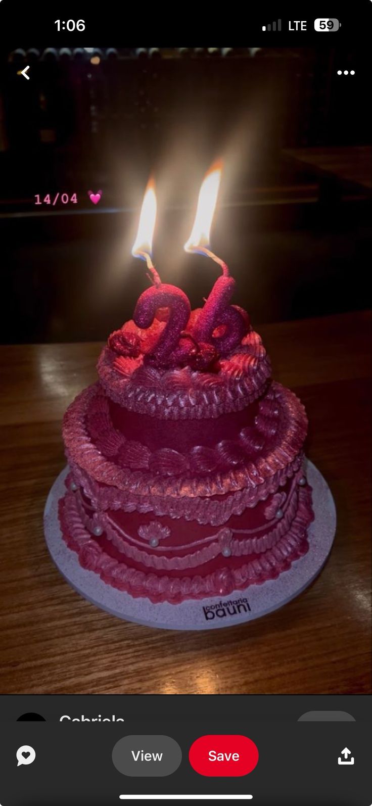 a red cake with two lit candles on it