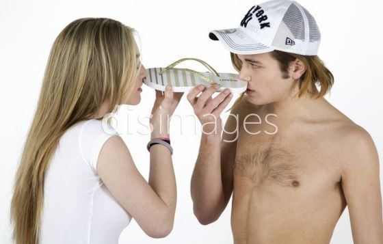 a man drinking from a bottle next to a woman wearing a white hat and no shirt