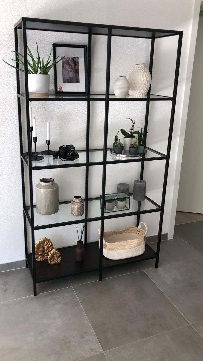 a black shelving unit with plants and pictures on it