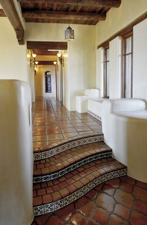 a long hallway with tiled floors and white urinals on either side of the stairs