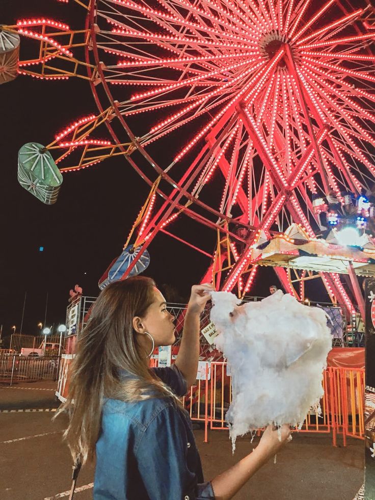 a woman holding up a piece of paper in front of a ferris wheel