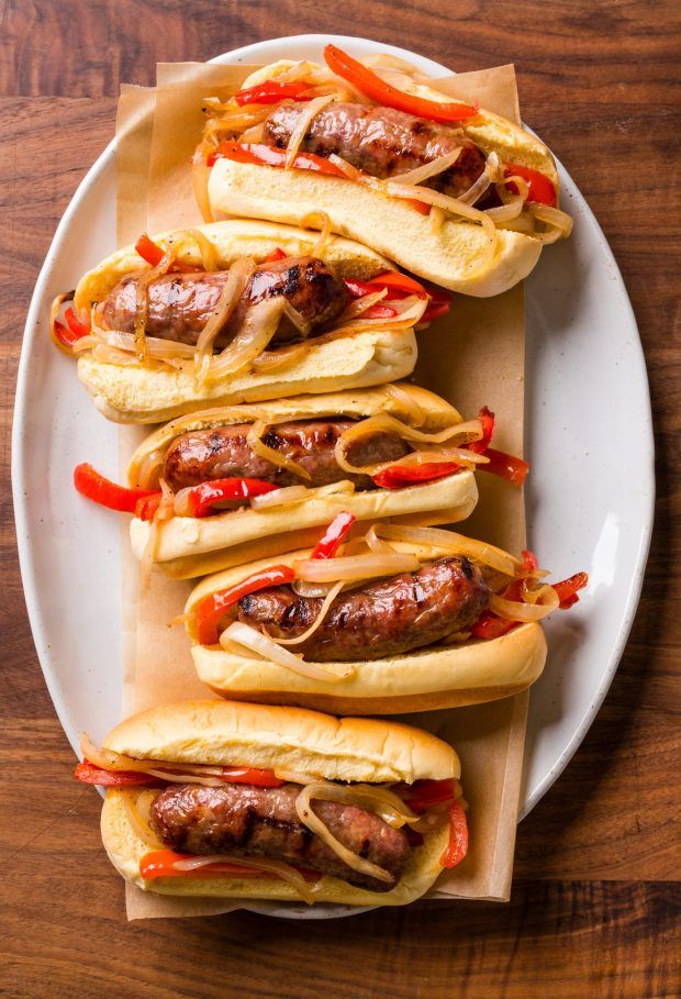 four hot dogs on buns with ketchup and peppers