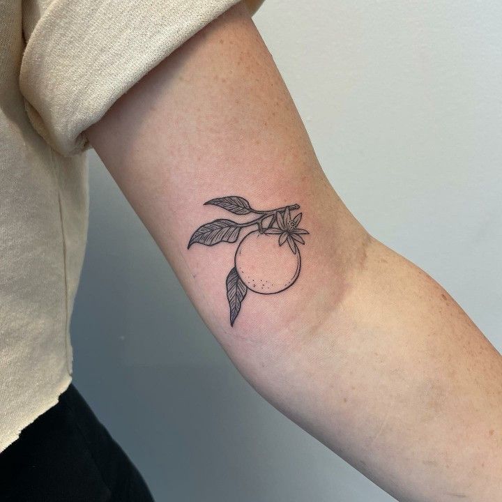 a woman's arm with a small tattoo of an apple and leaves on it