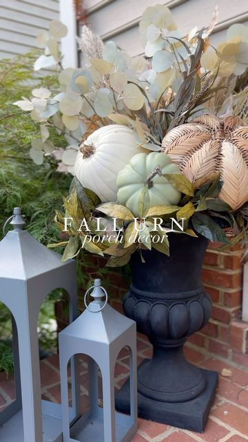 two gray lanterns sitting on top of a brick floor next to a vase filled with flowers