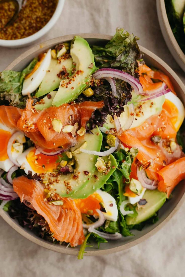 a salad with salmon, lettuce and other vegetables in bowls on a table