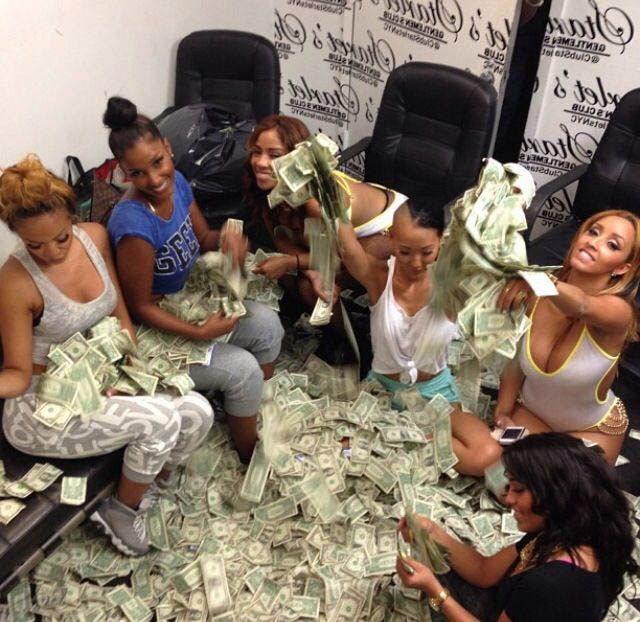 several women sitting on the floor with stacks of money