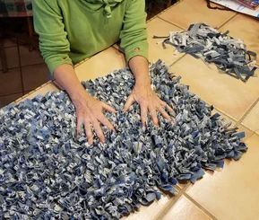 a woman sitting at a table with many pieces of fabric on the floor